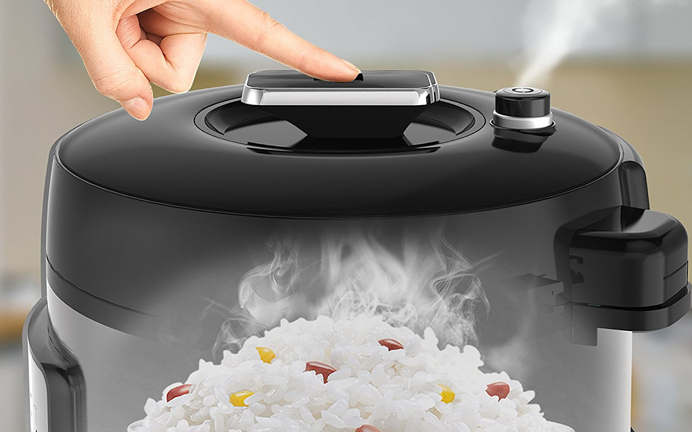 Steam is vented from a pressure cooker alongside cooked white rice.
