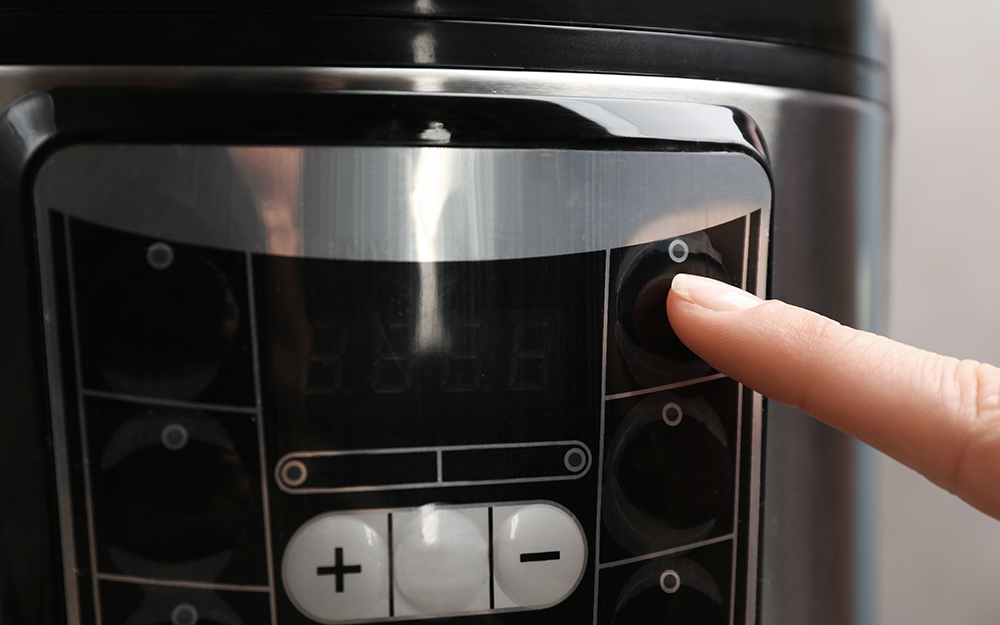 A person activates a pressure cooker via the front panel.