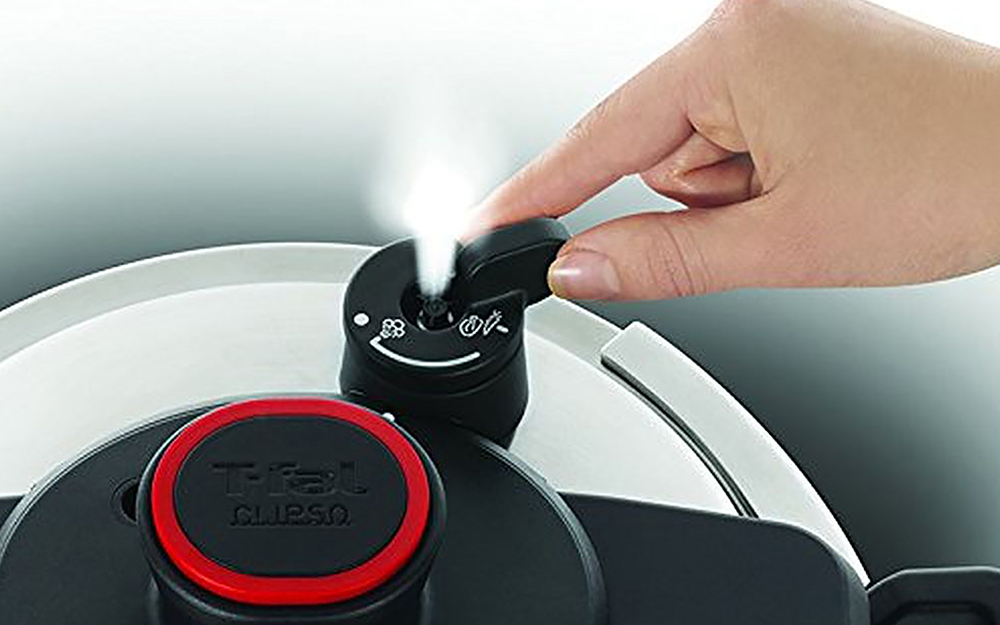 A person releases steam from a pressure cooker.