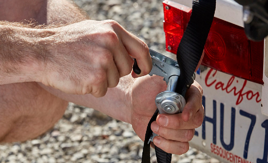 A person pumps the ratchet lever to tighten a ratchet strap.