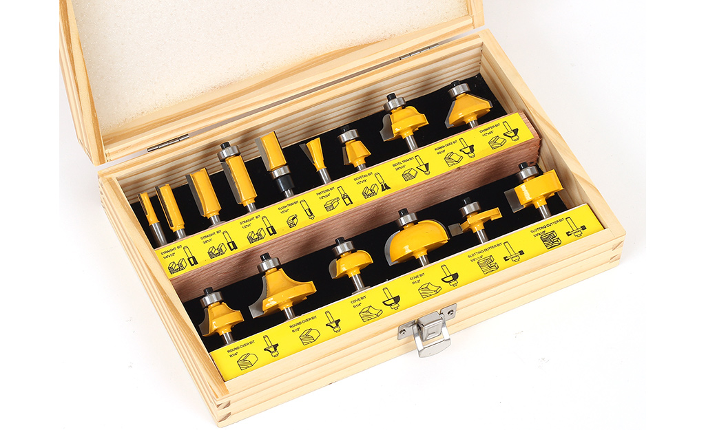 A set of router bits is organized in a wooden case.