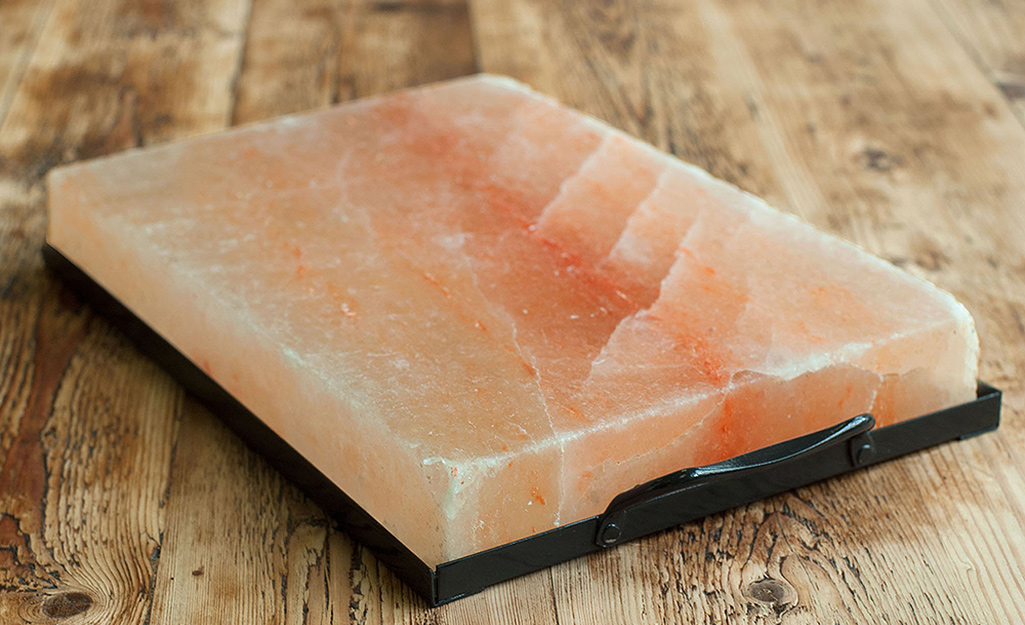 A pink salt rock for grilling sits on top of a metal tray.