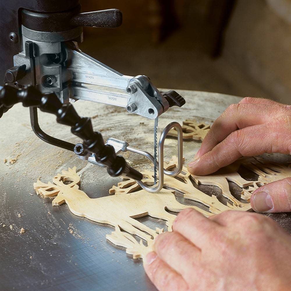 A person using a scroll saw to cut the shape of a deer.