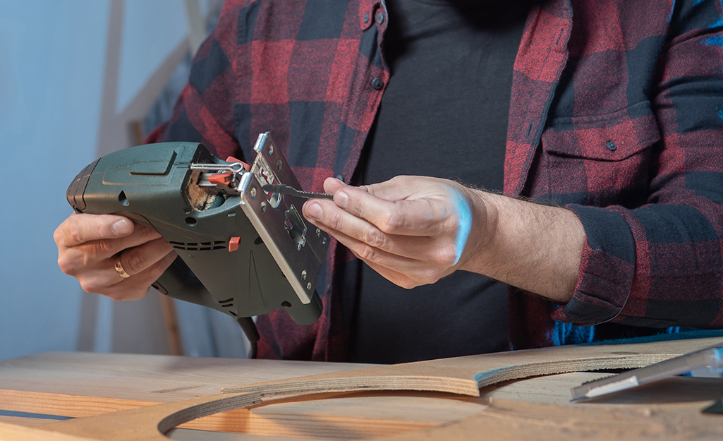 A person installs a blade in a scroll saw.