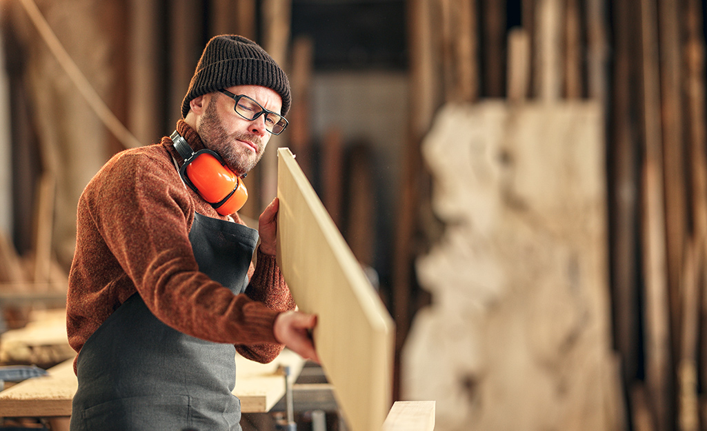 A man in a woodworking shop gets ready for a project.
