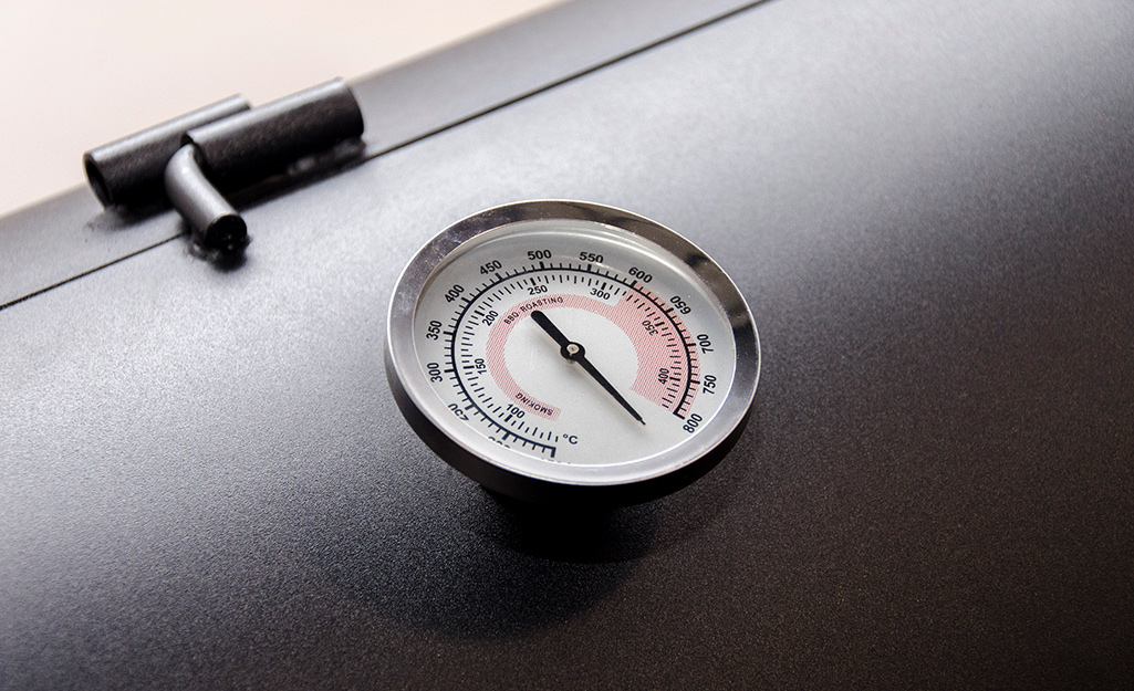 A thermometer on a grill.