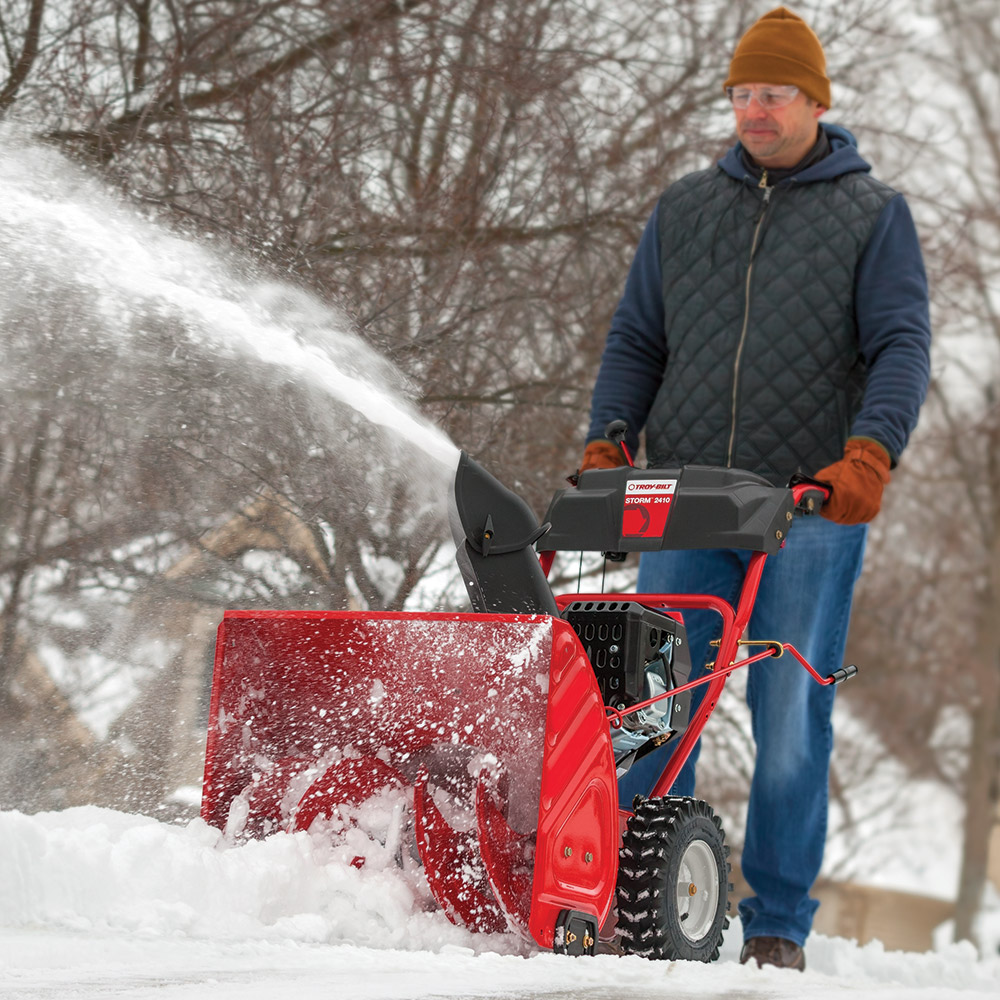 A person using a power snow blower to clear snow.