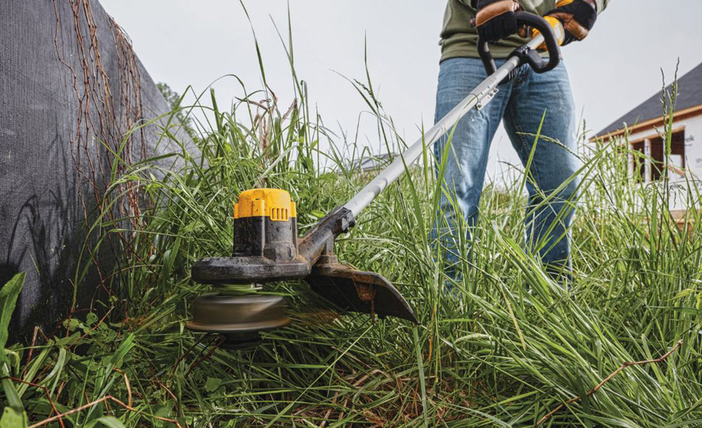 Close up of a person using a string trimmer.