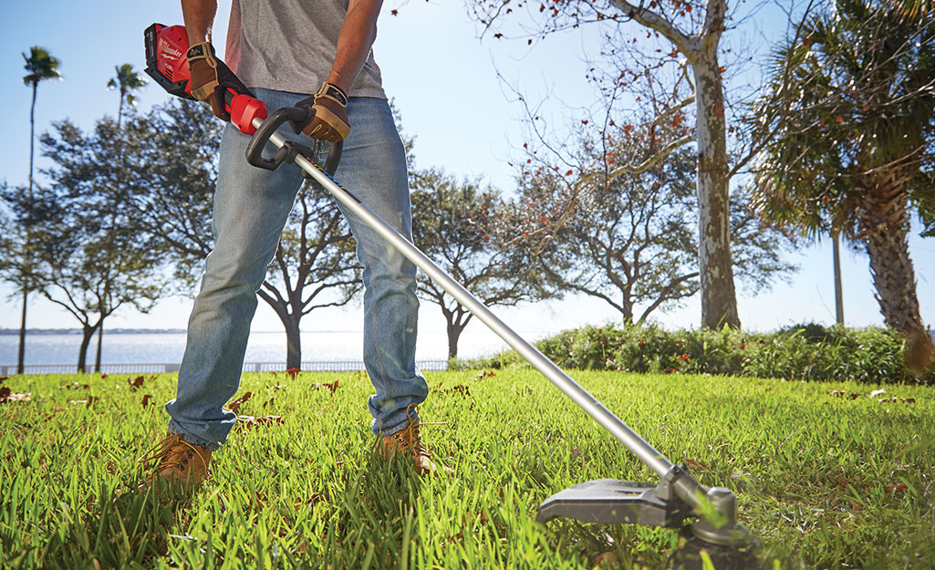 A man cuts grass using the string trimmer.