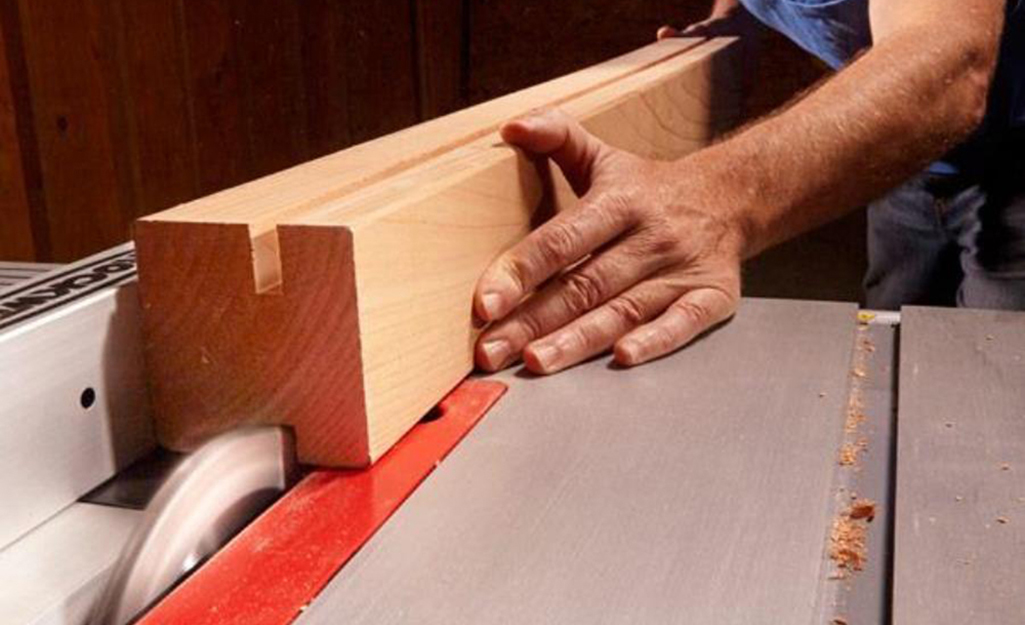 A person cutting a dado in a piece of wood.