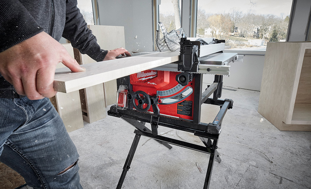A man cutting wood with a table saw.
