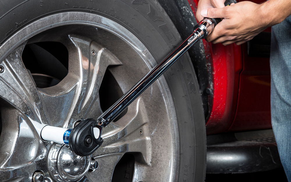 A person using a torque wrench on a car tire
