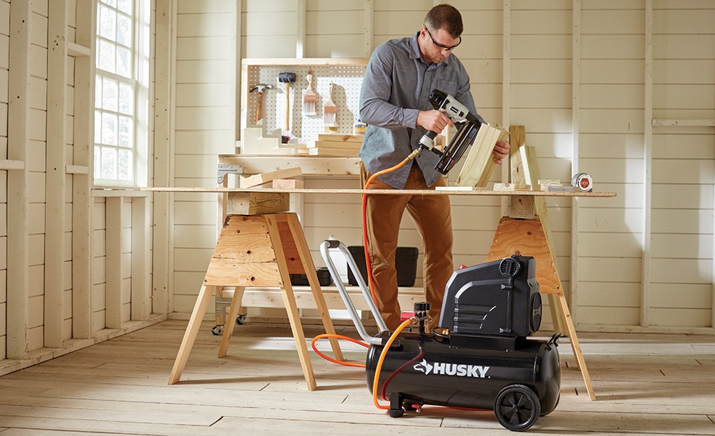 A person using a tool connected to an air compressor.