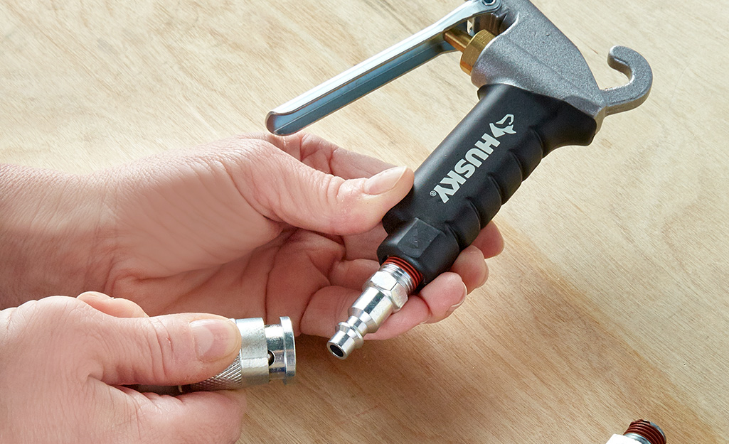 Two hands connecting a tool to the hose of an air compressor.