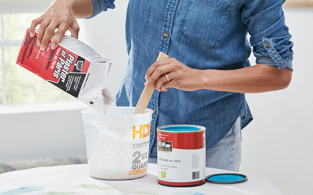 A person mixes plaster of Paris and latex paint. 