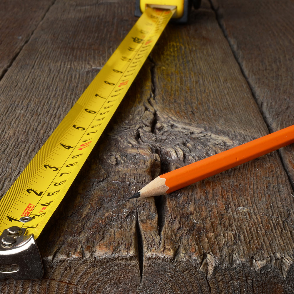 Measuring tape and a pencil laying on wood.