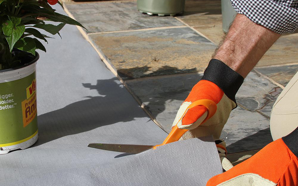 Person cutting grey Vigoro landscape fabric
