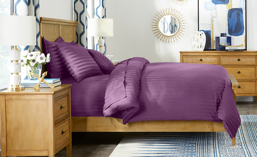 A purple comforter on a bed.