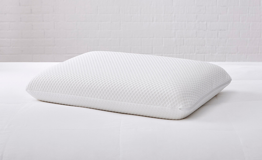 A memory foam pillow lays on a bed.