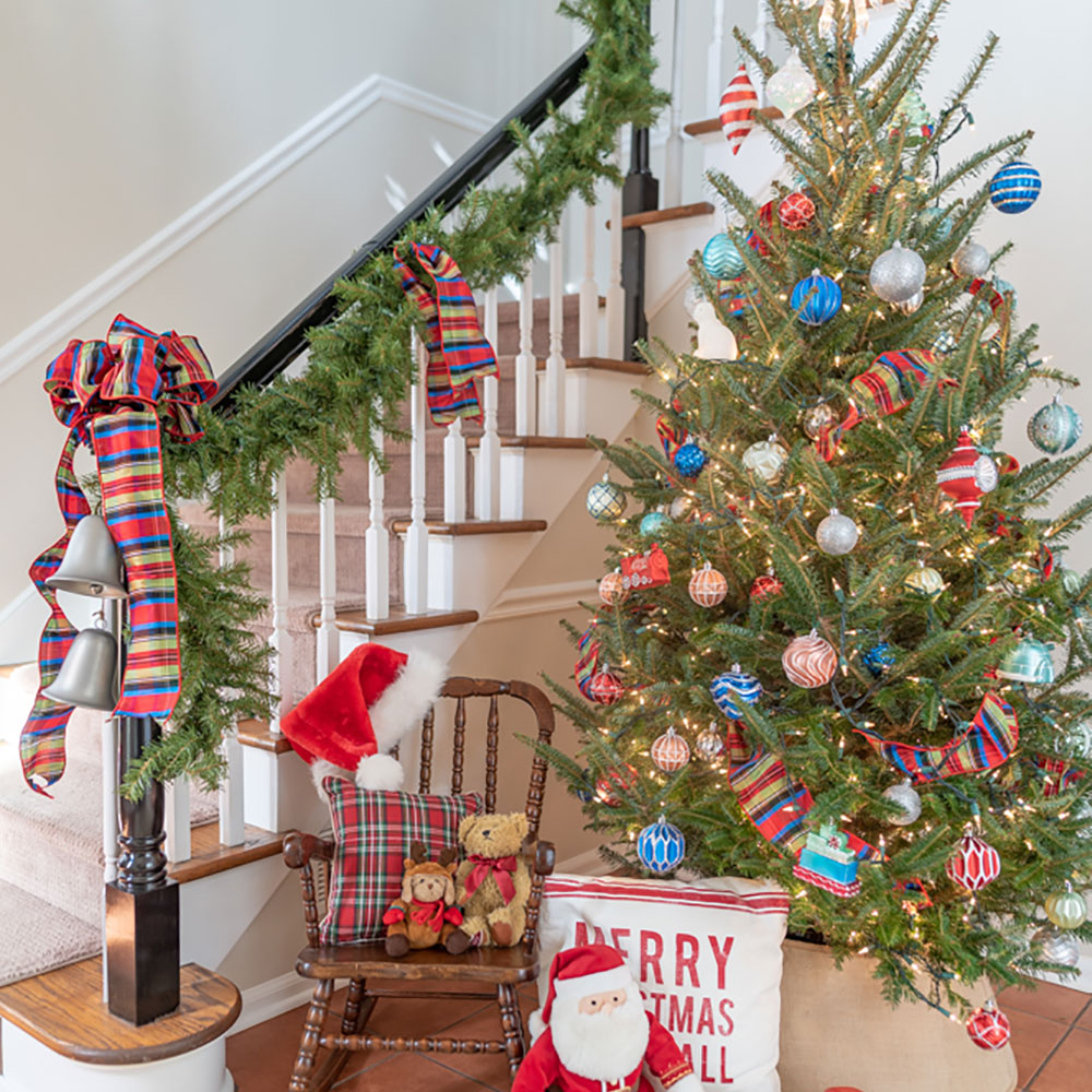A decorated Christmas tree in a corner near a stairway.