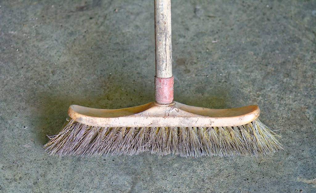 A broom sweeps a concrete floor.
