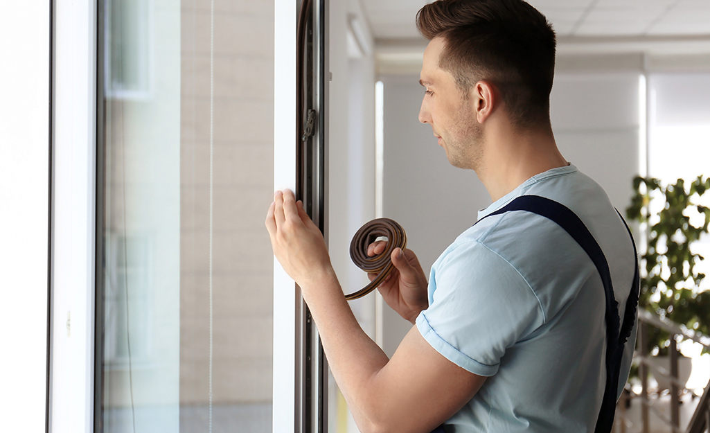 Someone adding foam-backed weatherproofing to casement windows.