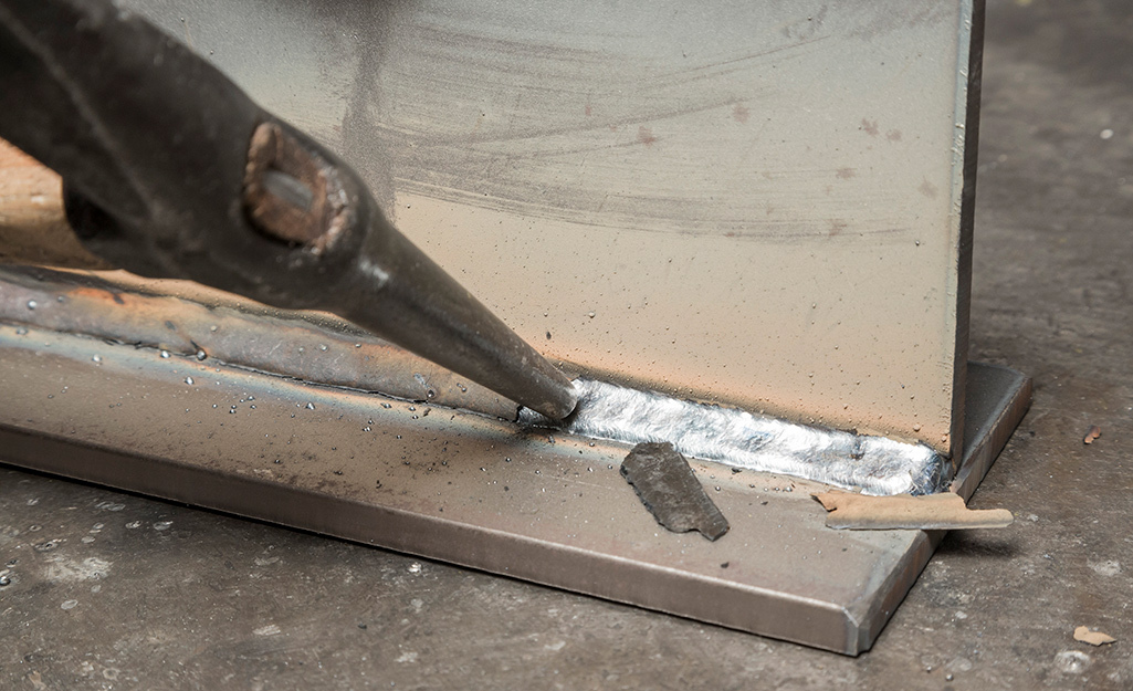 Slag being chipped away from a weld with a slag hammer. Slag being chipped away from a weld with a slag hammer.