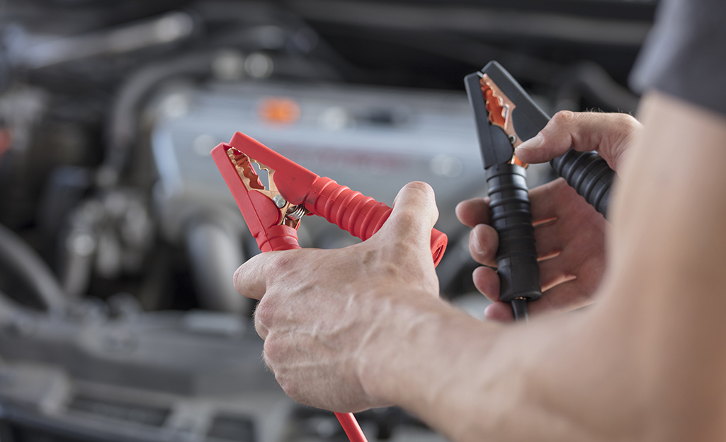 A person holds both ends of a jumper cable.