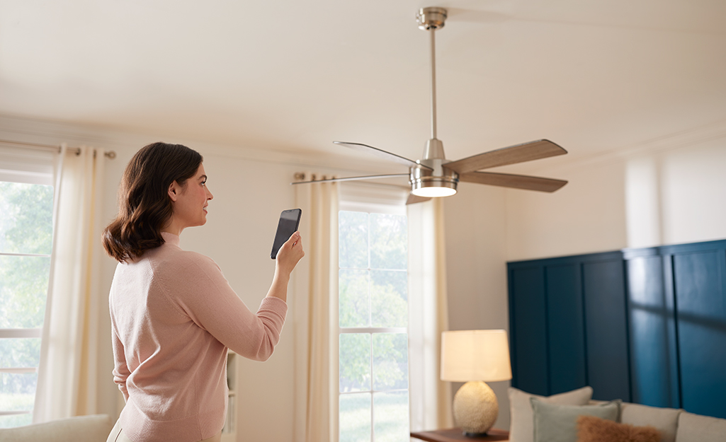 A person uses a wireless remote to operate a ceiling fan.