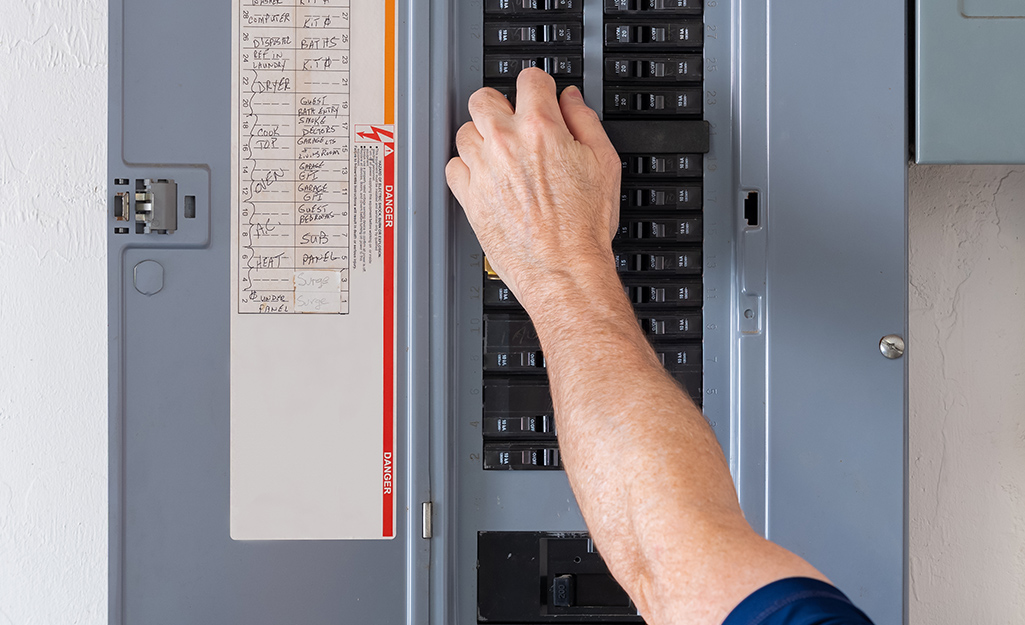 A person turns off the power at a breaker box.