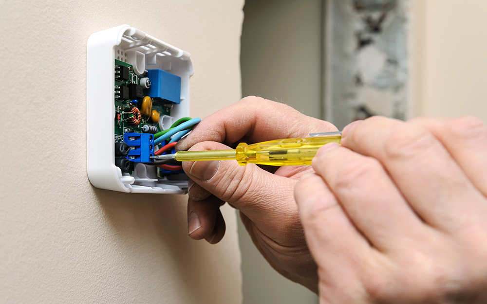 A person wiring a new thermostat