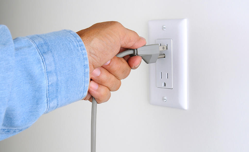 A person tests an electrical outlet.