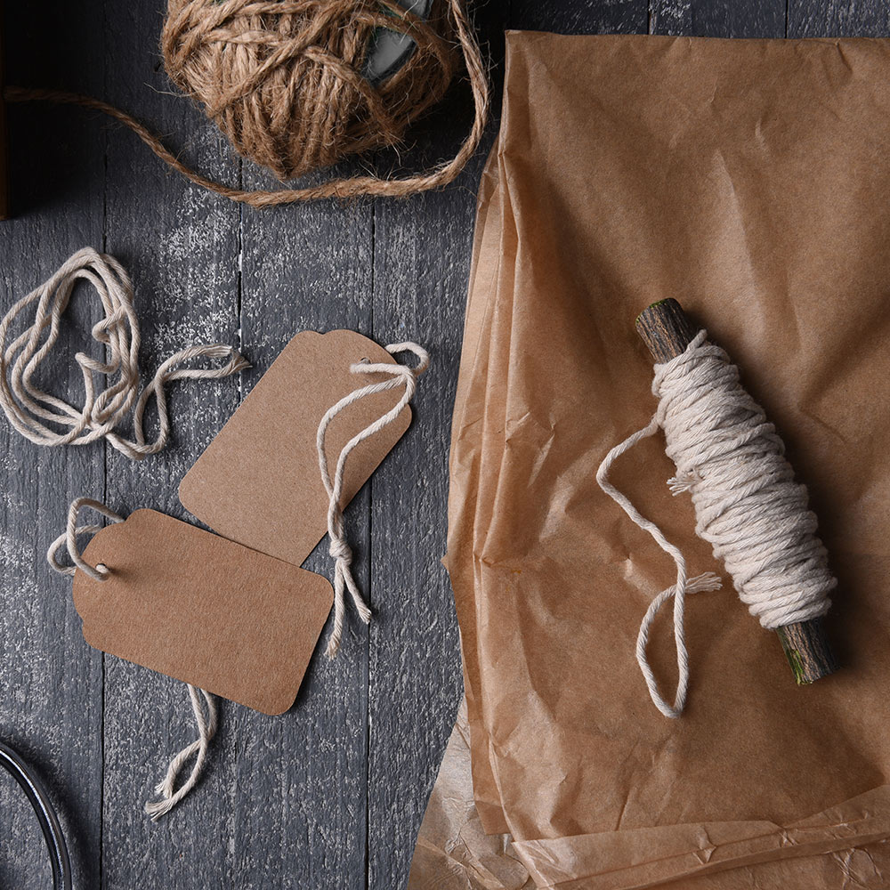 Gift tags, twine and brown tissue paper arranged on a table.