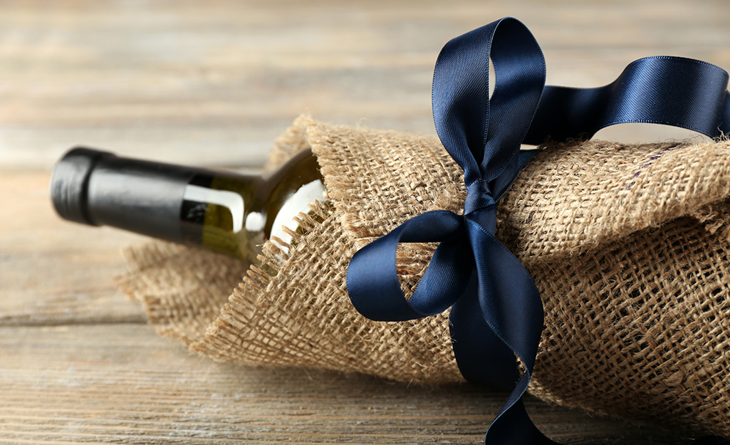 A wine bottle wrapped with burlap and tied with a ribbon.