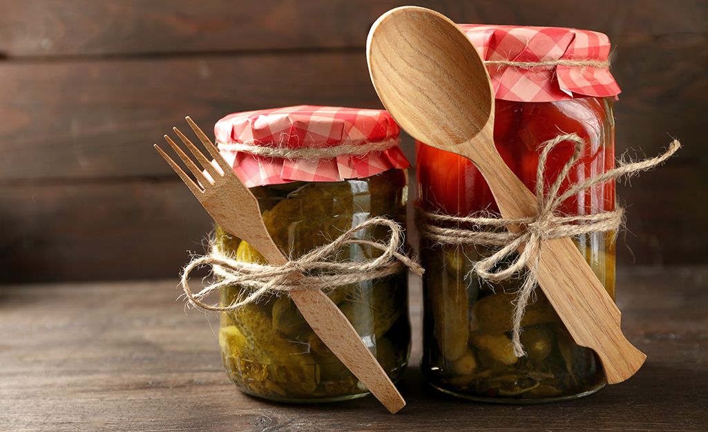 Wooden utensils tied with twine to canning jars.