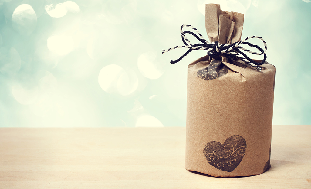 Brown paper wrapped around a cylindrical gift with ribbon tied to the top.