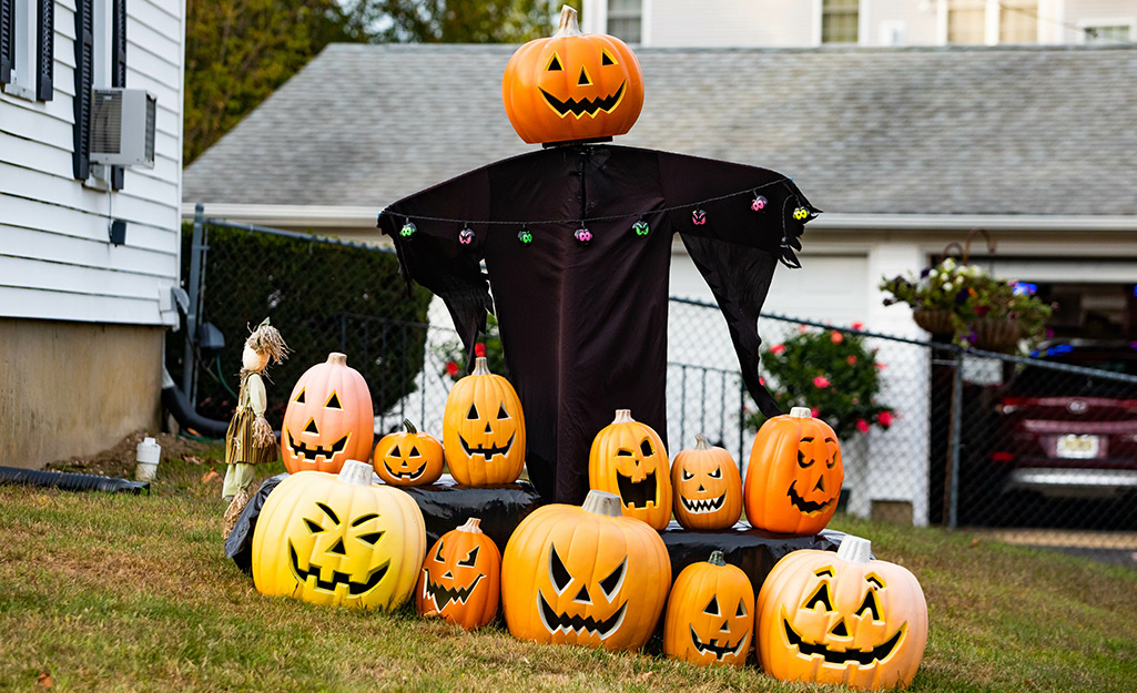 A pumpkin serves as the head for a scarecrow wearing a black robe that is surrounded by jack o'lanterns.