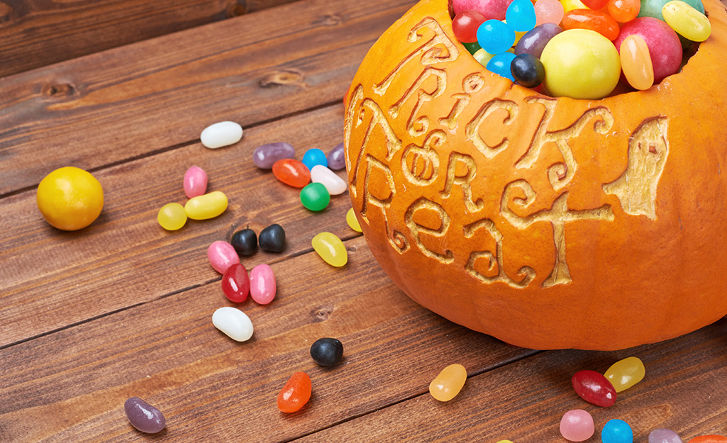 Jelly beans spill out of a pumpkin being used as a candy bowl.