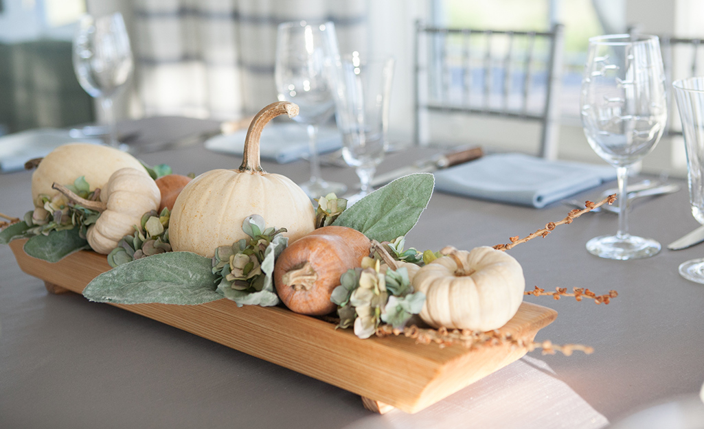 A table centerpiece features an arrangement of small pumpkins in white and orange.