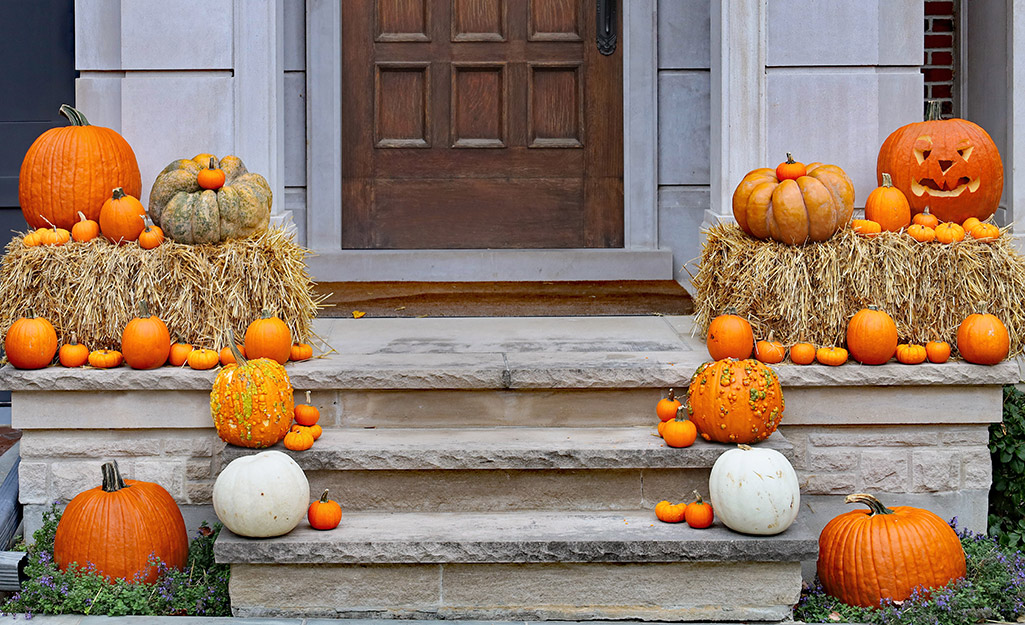 Pumpkins line the steps and sit on top of two hay bales on a small porch.
