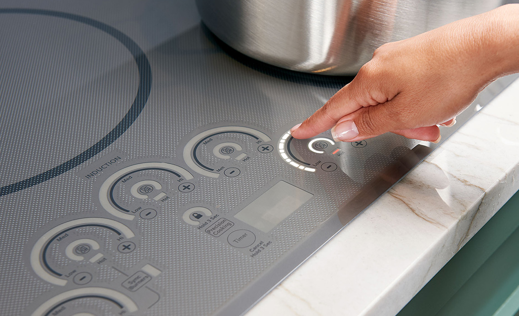 A person raising the temperature on an induction cooktop 