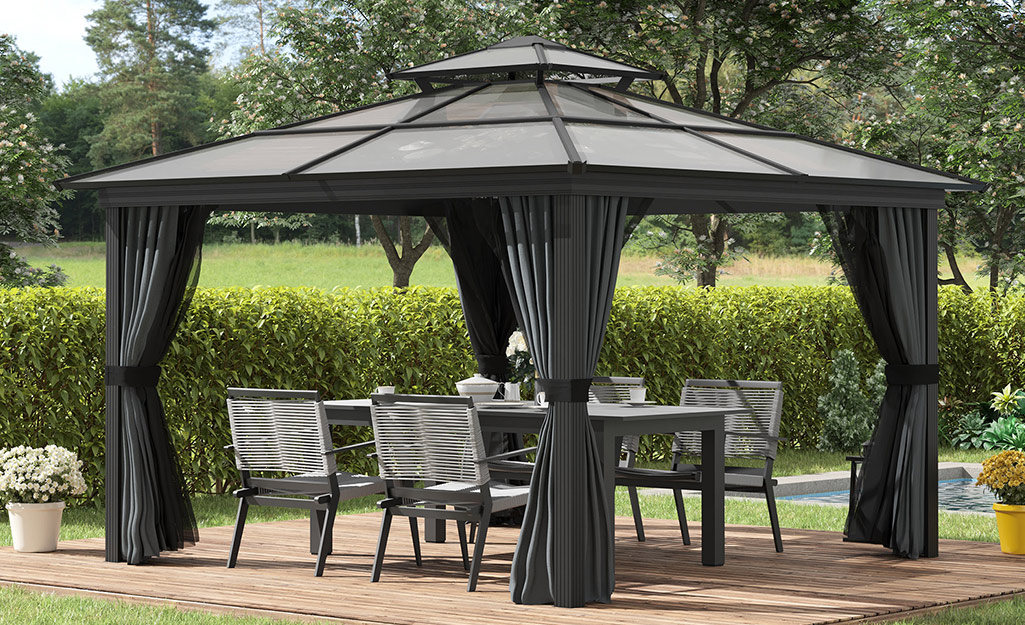 An outdoor dining set sits below a pergola on a patio.