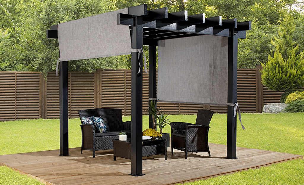 A small pergola with an adjustable canopy stands over an outdoor chair and matching love seat.