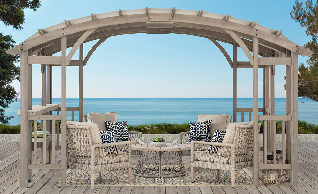 A seaside pergola covers a patio conversation set on a wooden deck.