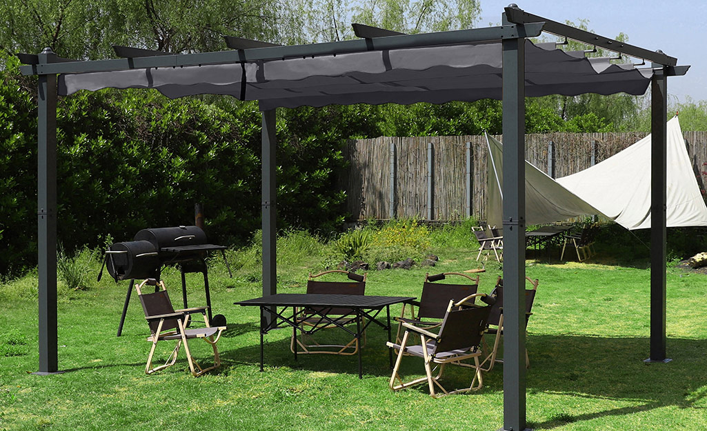 A canopy over a pergola provides shade folding chairs around a table.