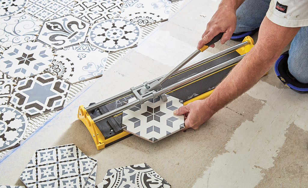 Man cutting tile with a manual tile cutter.