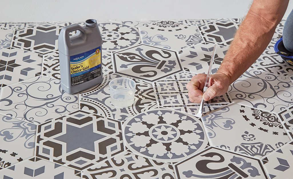 Person sealing grout using a small brush.