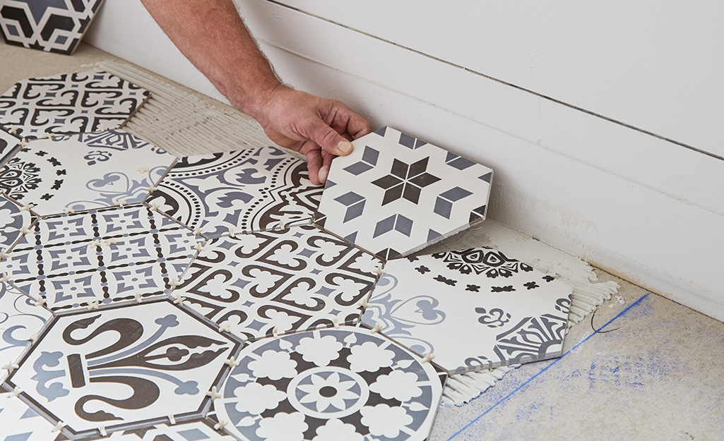 Person placing tile near a wall.