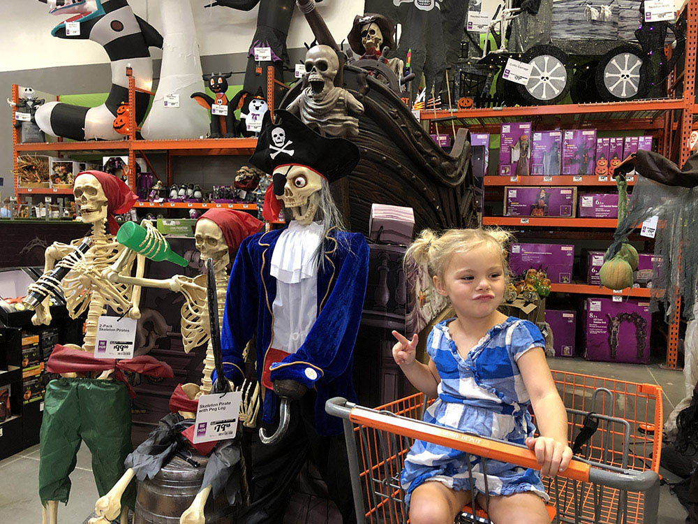 A child sitting in a shopping cart surrounded by Halloween decorations.