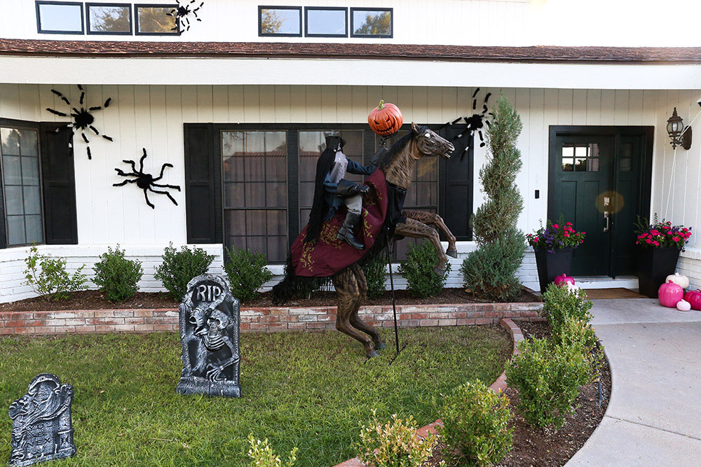 A Halloween yard display with a headless horseman and tombstones.